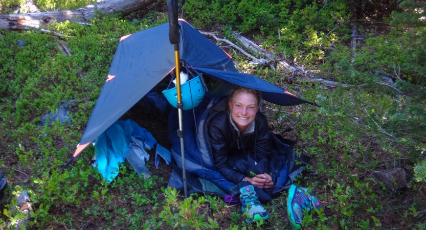 a person smiles from under a shelter in a green area